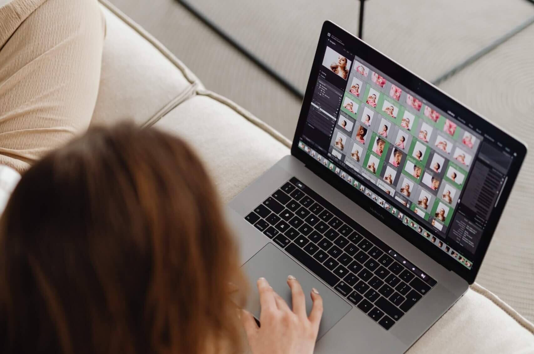 Na fotografii widać kobietę, która - używając laptopa - nakłada filtry na zdjęcia.